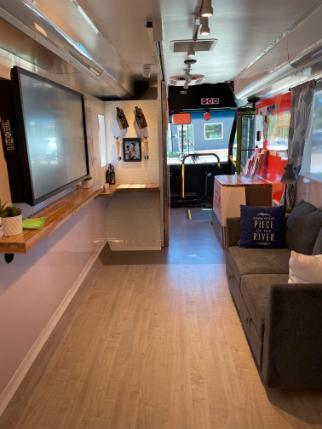 Inside of renovated Capstone Discovery Bus with sofa and TV area